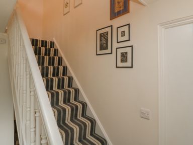 A staircase with striped carpet and framed pictures on a wall at Drover's in Sutton Mallet