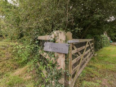 A wooden gate covered with vines and a sign that says Drovers at Drovers in Sutton Mallet