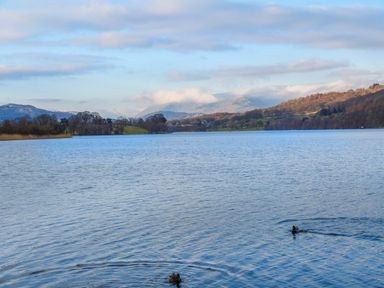 A lake with two ducks swimming and hills in the background at Buttermere in Sawrey near Hawkeshead
