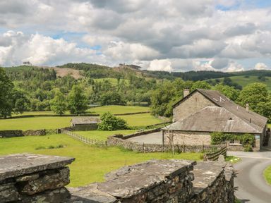 A stone house with a yard and surrounding green fields and trees at Buttermere in Sawrey near Hawkeshead