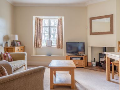 A living room with a window with curtains a television on a stand a coffee table a lamp and sofa at Buttermere Sawrey near Hawkeshead