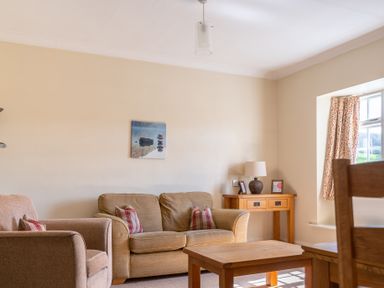 A living room with a sofa armchair wooden table sideboard lamp and window at Buttermere Sawrey near Hawkeshead