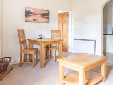 A dining area with a wooden table and two chairs next to a wooden door and a wooden coffee table at Buttermere in Sawrey near Hawkeshead