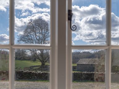 A view of a tree and stone building outside a window with a latch at Buttermere in Sawrey near Hawkeshead