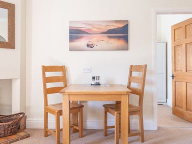 A wooden table with two wooden chairs and a landscape picture on the wall at Buttermere in Sawrey near Hawkeshead