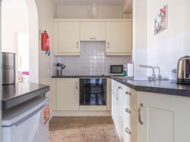 A kitchen with white cabinets black countertops an oven a microwave a kettle and a sink at Buttermere Sawrey near Hawkeshead
