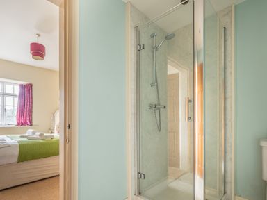 A bathroom with a glass shower enclosure and a view into a bedroom with a bed and window at Buttermere Sawrey near Hawkeshead