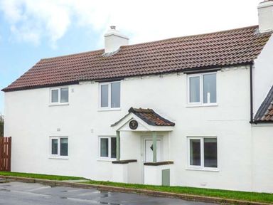 A white two-story house with a brown tiled roof and a small porch at Wold Cottage in Hunmanby