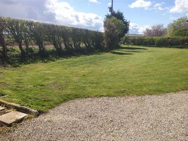 A lawn with a hedge and a gravel path at Wold Cottage in Hunmanby