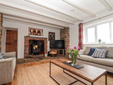 A living room with a fireplace and sofa at Wold Cottage in Hunmanby