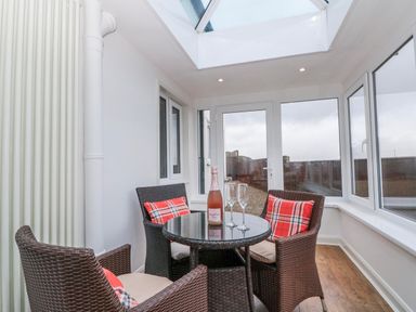 A conservatory with a table and chairs at Wold Cottage in Hunmanby
