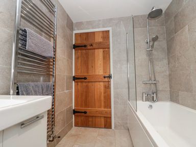 A bathroom with a towel radiator and a wooden door at Wold Cottage in Hunmanby