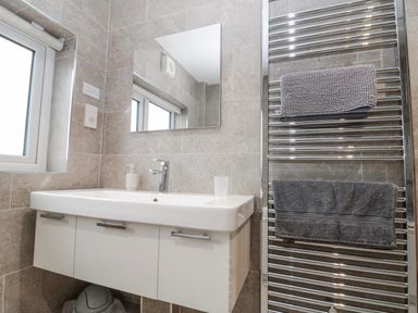 A bathroom with a sink, mirror, and towel radiator at Wold Cottage in Hunmanby