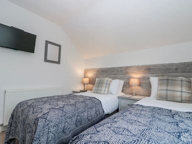 A bedroom with two twin beds and a television at Wold Cottage in Hunmanby