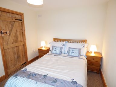 A bedroom with a wooden double bed and two bedside tables each with a lamp at Ffynnon Gower in Llangower near Bala