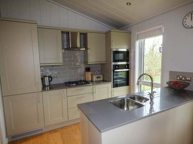A kitchen with built-in appliances a sink on a countertop and cabinets at Shepherd Lodge Allithwaite near Grange-over-Sands