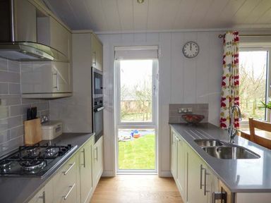 A kitchen with countertops a stove a sink a window and a door at Shepherd Lodge in Allithwaite near Grange-over-Sands