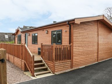 A wooden lodge with steps and a railing leading to the entrance at Thorntree Lodge in Rowsley