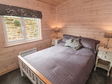 A bedroom with a bed and bedside tables with lamps at Thorntree Lodge in Rowsley