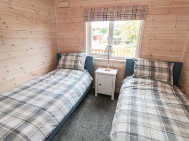 A bedroom with two single beds and a nightstand under a window at Thorntree Lodge in Rowsley