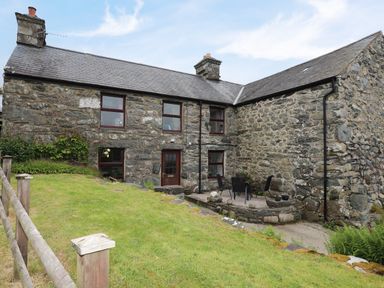 A stone cottage with a patio area and outdoor furniture at Hendy Cottage Llanbedr near Harlech