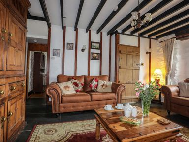 A living room with brown sofas wooden coffee table with tea set and flowers at Hendy Cottage in Llanbedr near Harlech