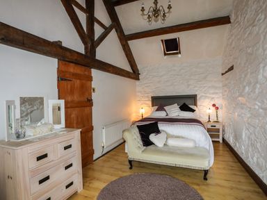 A bedroom with a bed nightstands and a dresser with a mirror at Hendy Cottage in Llanbedr near Harlech