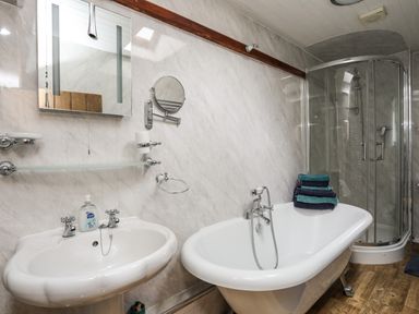 A bathroom with a white pedestal sink mirror bathtub with towels and a corner shower at Hendy Cottage Llanbedr near Harlech