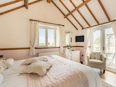 A bedroom with a bed pillows a chest of drawers air conditioner and an armchair at Y Becws Llanbedr near Harlech