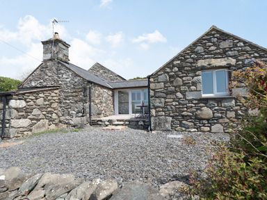 A stone exterior cottage with a patio table and chairs at Y Becws in Llanbedr near Harlech