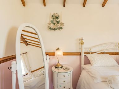 A bedroom with a white bed and bedside table with lamp and standing mirror at Y Becws in Llanbedr near Harlech