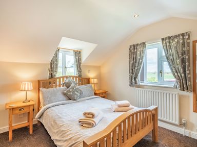 A bedroom with a wooden bed and matching bedside tables with lamps at Harvest Moon in Grundisburgh