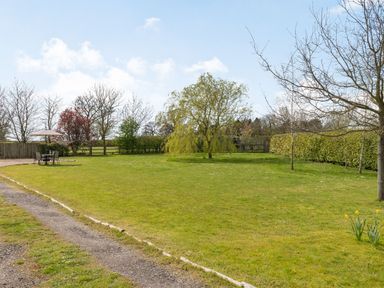 A lawn with trees and outdoor table with umbrella in a garden at Harvest Moon in Grundisburgh