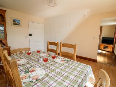 A dining room with a table set for four with glasses of red drink and floral plates at Green Cottage in Pant-y-Dwr near Rhayader