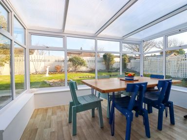 A conservatory with a table and chairs at Merlin's Retreat in Tintagel