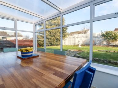 A conservatory with a wooden table and chairs at Merlin's Retreat in Tintagel