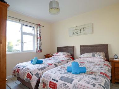 A bedroom with two beds and nightstand at Merlin's Retreat in Tintagel