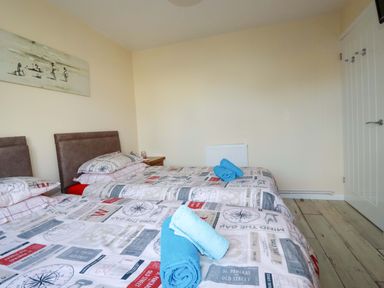 A bedroom with two beds and towels at Merlin's Retreat in Tintagel