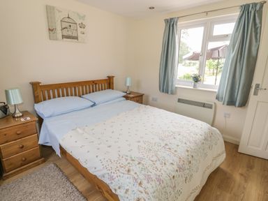 A bedroom with a wooden bed and blue curtains at Lawn Lodge in Ashleworth