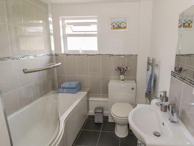 A bathroom with a bathtub shower combination toilet sink and a window at Lawn Lodge in Ashleworth