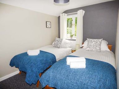 A bedroom with two single beds with blue blankets and white towels at Corner Cottage in Reynoldston near Swansea