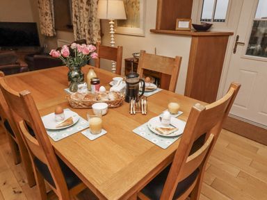 A dining room with a table set for breakfast at Long Cart Cottage in Embleton