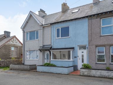 A row of terraced houses with a blue house in the middle on a street at 2 Tregof Terrace in Cemaes Bay