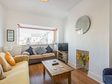 A living room with two sofas a wooden coffee table a television and a decorative mirror at 2 Tregof Terrace in Cemaes Bay
