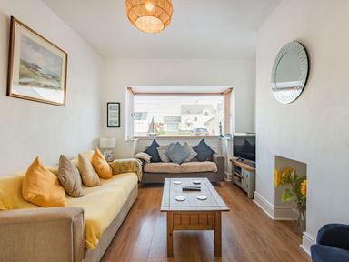 A living room with two sofas a wooden coffee table a television a window with blinds and flowers in a vase at 2 Tregof Terrace in Cemaes Bay
