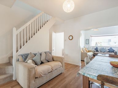 A living room with beige sofas cushions a staircase a dining table and chairs at 2 Tregof Terrace in Cemaes Bay