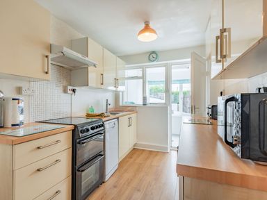 A kitchen with black stove white dishwasher microwave and wooden countertops at 2 Tregof Terrace in Cemaes Bay