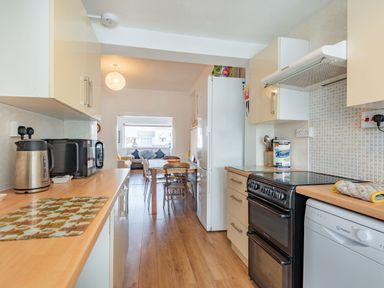 A kitchen with wooden countertops appliances and a dining area with chairs and a sofa at 2 Tregof Terrace in Cemaes Bay