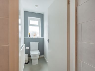 A bathroom with a white toilet near a frosted window and a white door at 2 Tregof Terrace in Cemaes Bay