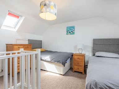 A bedroom with two single beds wooden dresser and nightstand under a skylight at 2 Tregof Terrace in Cemaes Bay